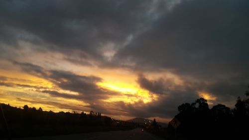 Silhouette of trees against dramatic sky during sunset