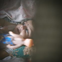 Cute baby girl with toy lying on bed at home