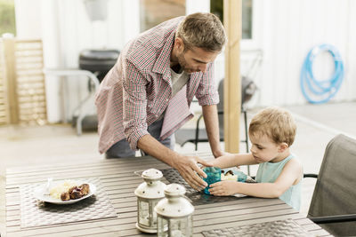 Father feeding son while standing at restaurant