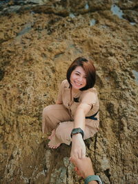 Portrait of smiling young woman standing on rock