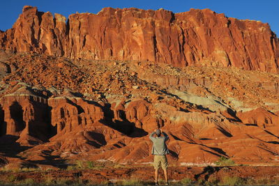 Rear view of man standing against rocky cliff