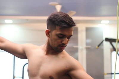 Shirtless young man flexing muscles in gym