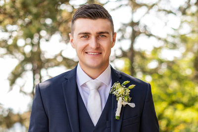 Handsome young groom wearing elegant and stylish dark blue suit outdoors portrait. 