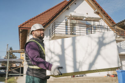 Construction worker holding polystyrene foam in front of house