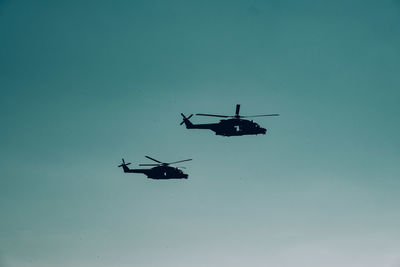 Silhouette of helicopters against clear sky