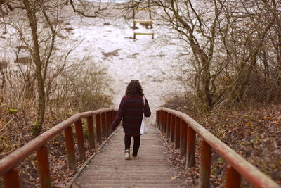 Rear view of woman walking on footbridge