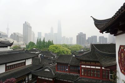 View of roofed structures with tall buildings in distant