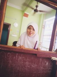 Portrait of smiling girl in hijab seen through window