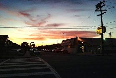 Road passing through city at sunset