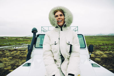 Portrait of smiling young woman on field against sky