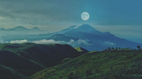 Distant view of birds flying over mountains