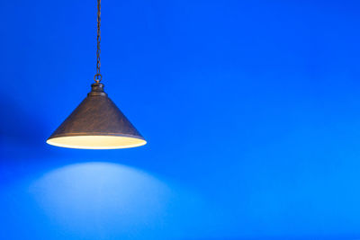 Low angle view of illuminated lamp against blue sky