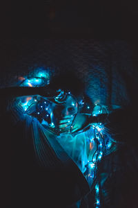 High angle view of woman holding illuminated light while lying on bed