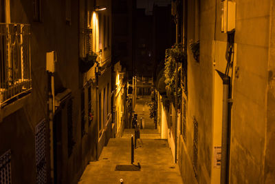 View of alley amidst buildings at night