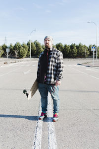 Portrait of a modern man holding the longboard.