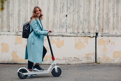 Full length of woman standing on push scooter