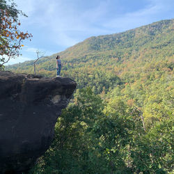 Man standing on rock against sky