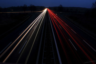 Light trails on road against sky at night