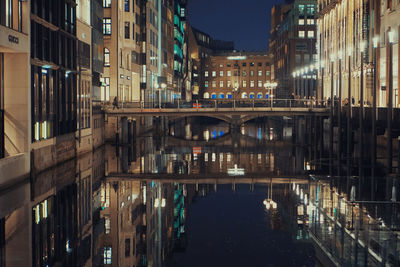 Bridge over canal amidst buildings in city at night
