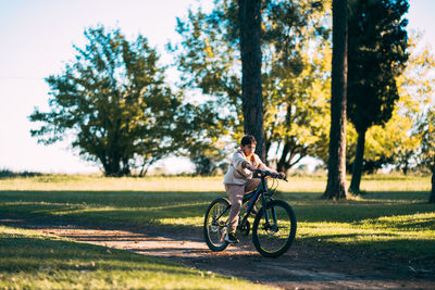 Full length of girl riding bicycle on field