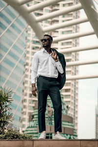 Young man wearing sunglasses standing against built structure