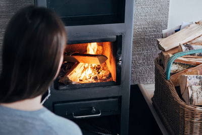 Rear view of woman by fireplace at home