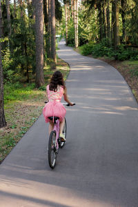 Rear view of man riding motor scooter on road