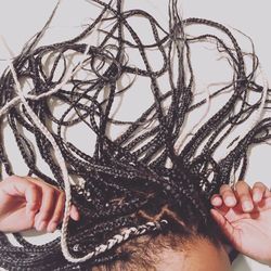 Cropped image of woman dreadlocks against wall