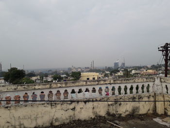 Bridge over river by buildings in city against sky