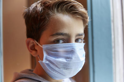 Close-up portrait of boy wearing mask at home