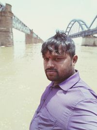 Portrait of young man against bridge