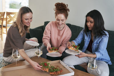 Smiling female friends eating food at home