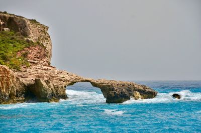 Rock formation in sea against clear sky