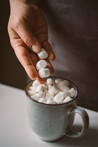 Woman puts marshmallows in a hot cocoa mug. festive atmosphere