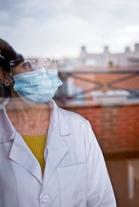 A woman in a white coat looks through the window