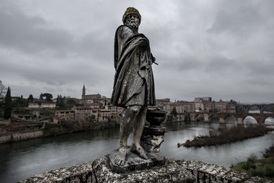 Statue by river against sky