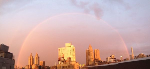Panoramic view of rainbow over buildings in city against sky