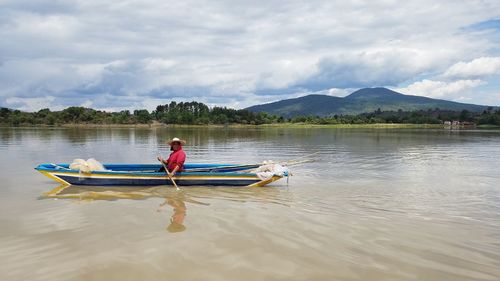 Woman sitting in fishing boat on lake