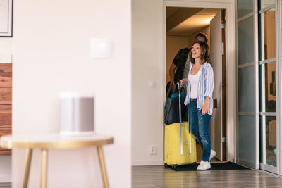 Excited couple with luggage entering in apartment during vacation