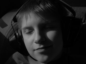 Close-up of boy listening to music while lying down on bed