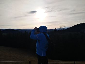 Rear view of woman standing on mountain against sky