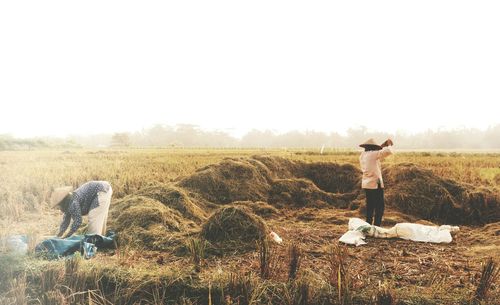 Farmers working in farm against clear sky