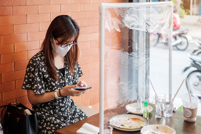 Woman using smart phone sitting at cafe