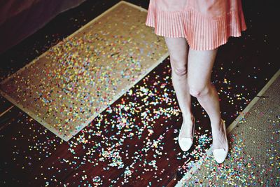 Low section of woman in short skirt with confetti on floor