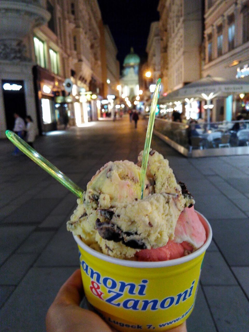 CLOSE-UP OF HAND HOLDING ICE CREAM AT NIGHT