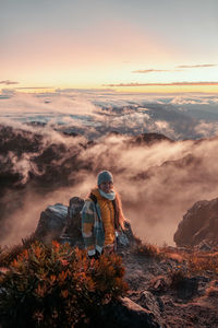 Rear view of man standing on mountain against sky during sunset