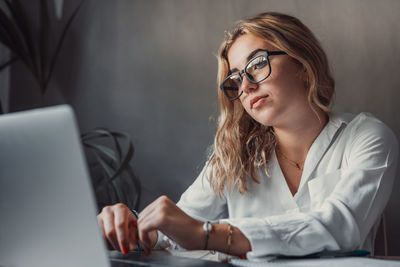 Portrait of young woman using laptop at table