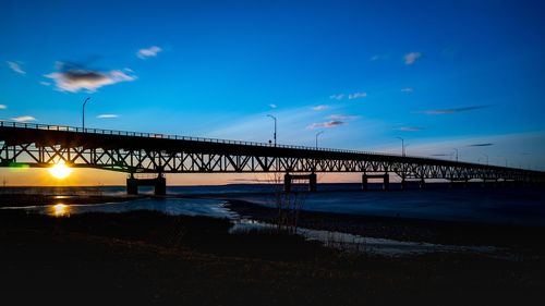 Silhouette bridge over sea against sky during sunset