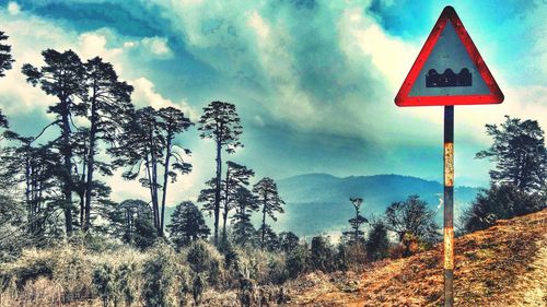 Road sign against cloudy sky