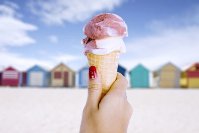 Close-up of hand holding ice cream cone on beach